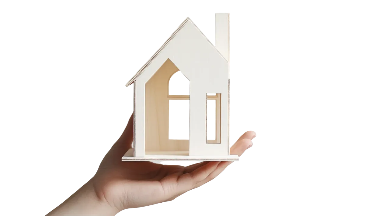 A hand holding a small wooden model house